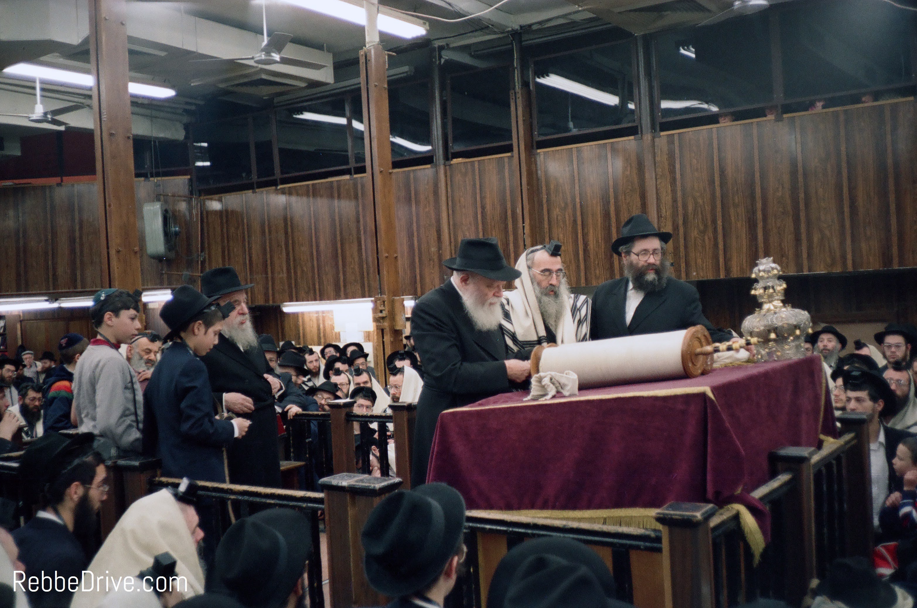 The Lubavitcher Rebbe standing at an open Torah scroll during the Torah reading in 770.